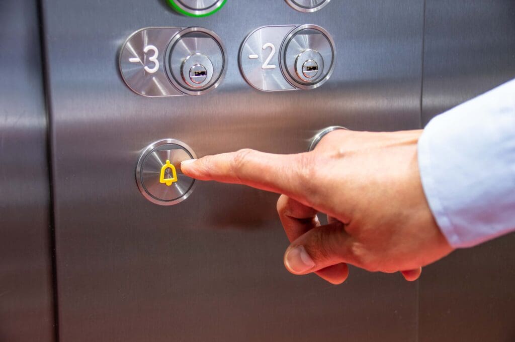Close up of a hand pressing the lift alarm button